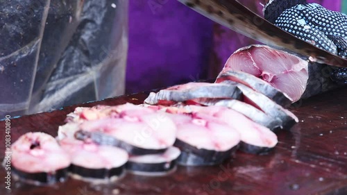 A close-up of fresh fish being expertly sliced into steaks on a wooden cutting board, captured in smooth HD slow motion.