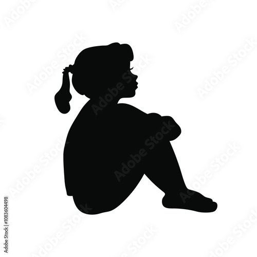 A girl is sitting on the ground. She is wearing a ponytail. She is looking down