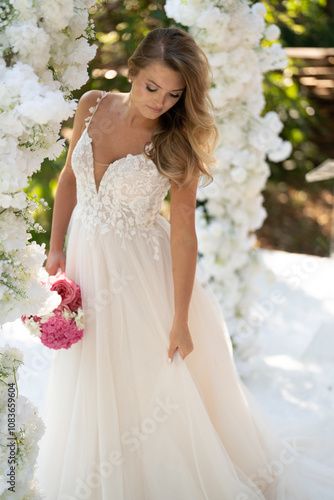 Beautiful bride on white wedding dress with bridal bouquet photo