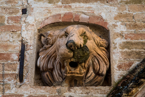 Il muso del leone scolpito sulla facciata di un palazzo storico di Portogruaro, in Veneto, come ornamento photo