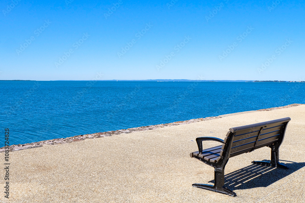 Fototapeta premium A beautiful sunny day, clear and blue sky, sunshine and seagulls flying along the sea at Wynnum jetty, Manly, Suburbs of Brisbane CBD 