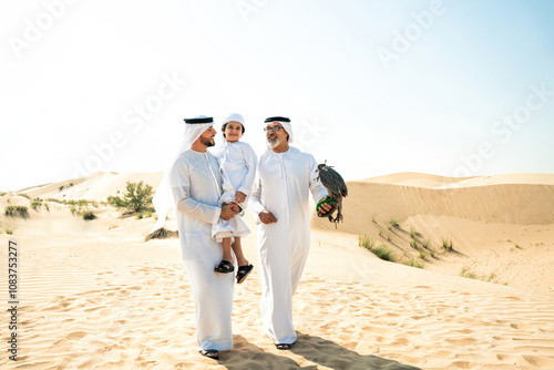 Three generation family making a safari in the desert of Dubai. Grandfather, son and grandson spending time together in the nature and training their falcon bird. photo