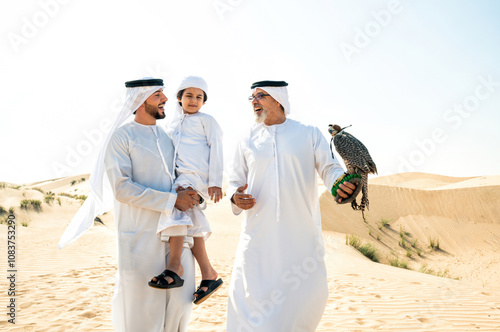 Three generation family making a safari in the desert of Dubai. Grandfather, son and grandson spending time together in the nature and training their falcon bird.