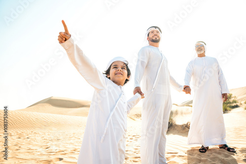 Three generation family making a safari in the desert of Dubai. Grandfather, son and grandson spending time together in the nature and training their falcon bird. photo