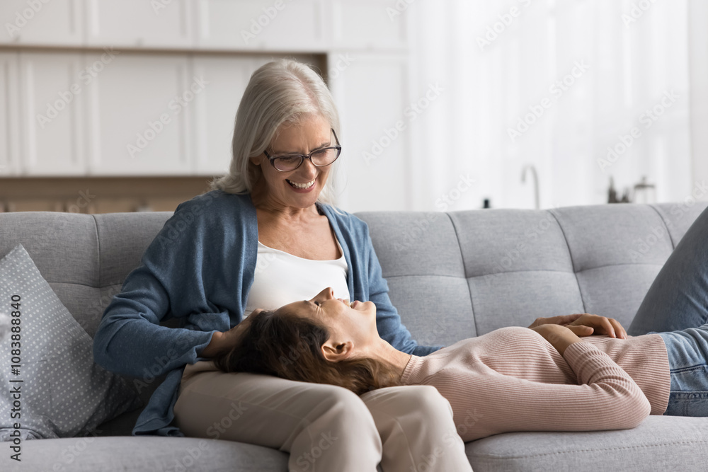 Φωτογραφία Older 65s pensioner woman enjoy time and pleasant talk with grown up young adult daughter, lying on loving moms knees smile lead trustworthy conversation during her visit at caring mums house