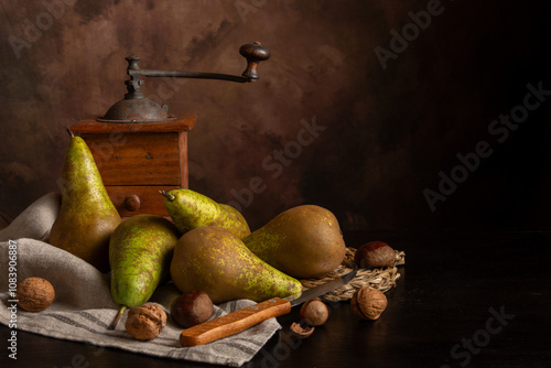 View of pears on cloth on table with nuts, knife and grinder, dark background, horizontal, with copy space