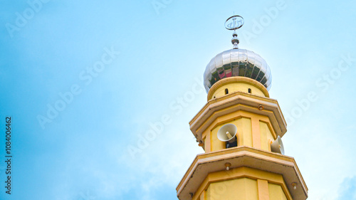 Yellow, orange mosque tower. Isolated from blue cloud background in Batu Tomok village, Simalungun photo