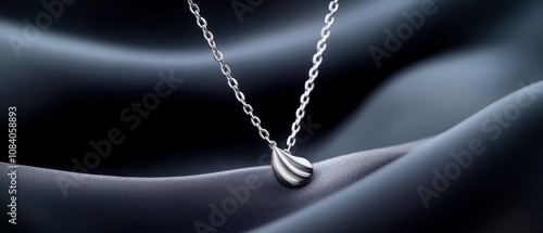 A silver necklace with a tear shaped pendant on a chain photo