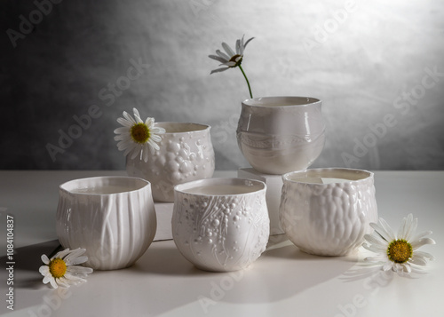 Porcelain white cups with chamomile flowers on a light table