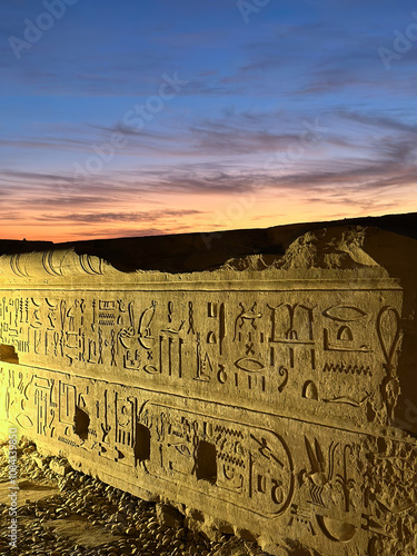 ancient carved wall with hieroglyphics outside Kom Ombo temple at sunset