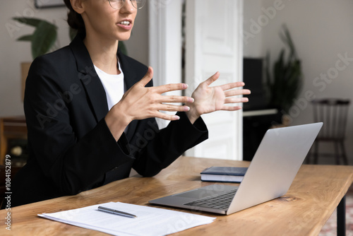 Professional woman, lawyer or solicitor provide information, lead online consultation with client using videoconference on laptop, sit at workplace desk, make speech, explain details, help with advice