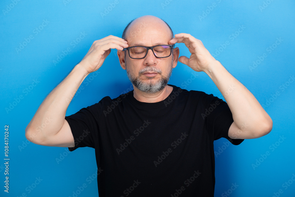 Naklejka premium Bearded, bald man wearing prescription glasses and a black shirt gesturing with his arms to the camera. Confident and calm.