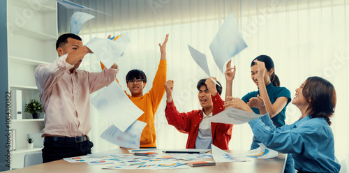 Excited and happy startup company employee celebrate and throw paper in the air after make successful business. Teamwork and positive environemtn create productive and supportive workplace. Synergic photo