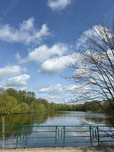 Serene Lakeside View With Clear Blue Sky And Lush Greenery