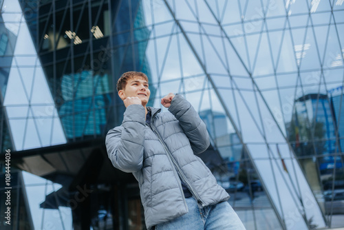 Happy teenage boy celebrating in the city, joyful expression on urban backdrop