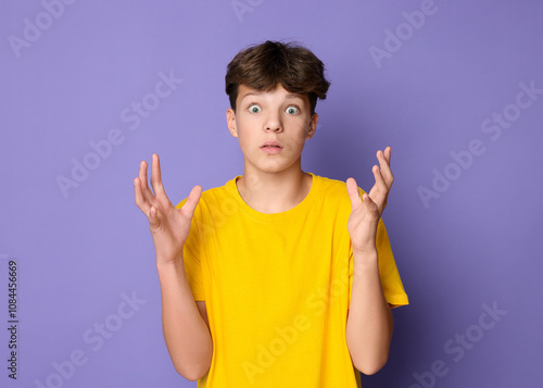 Portrait of scared teenage boy on violet background photo