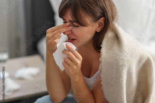 Woman wrapped in blanket suffering from sinusitis at home