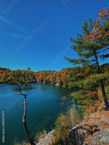 Scenic view of Pink Lake in Gatineau Park, surrounded by autumn colors, lush forest, and clear blue water – perfect fall getaway photo