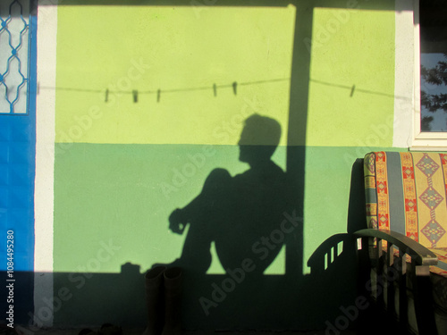 Canvas Print Silhouette of a seated figure cast on a vibrant green wall evoking introspection