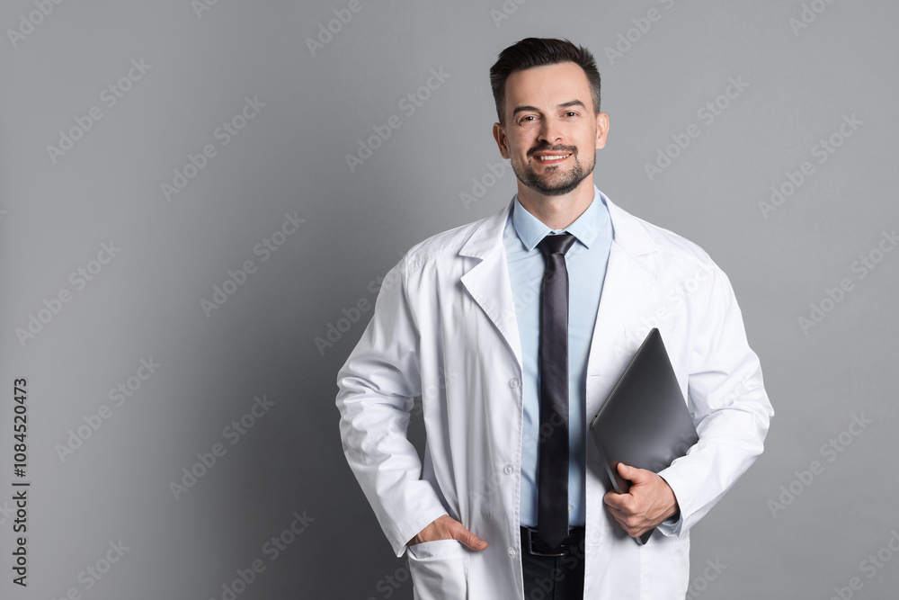 Smiling doctor with laptop on grey background Smiling doctor with laptop on grey background