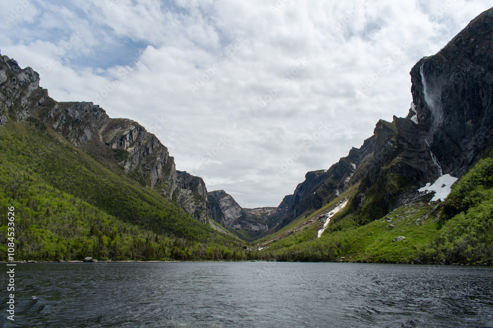 Fototapeta premium The eastern end of Western Brook Pond, where the fjord meets, features tranquil waters and towering cliffs, capturing the majestic beauty of Gros Morne National Park.