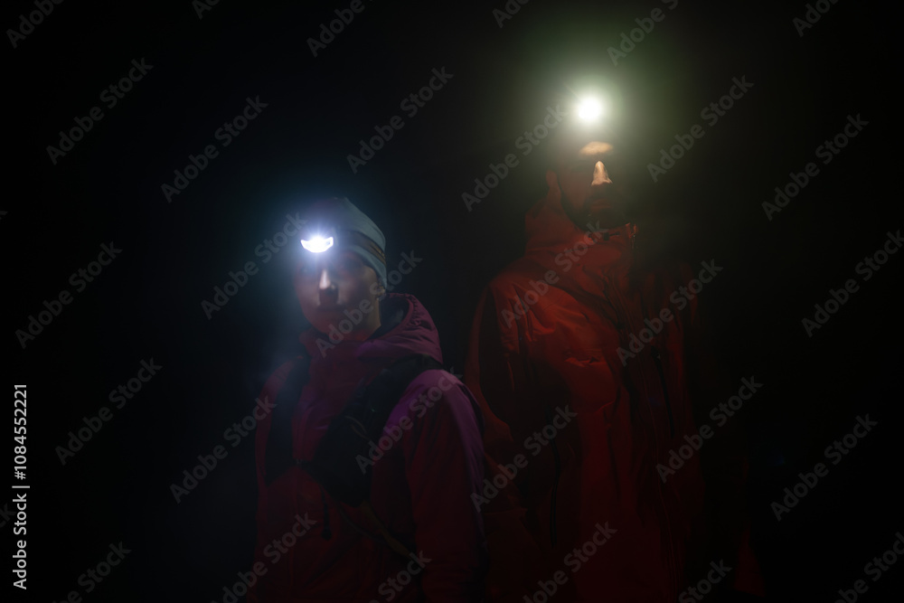 Fototapeta premium trail runners couple portrait while preparing for an early morning run in the night time with a headlamp