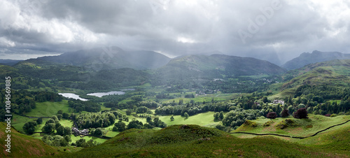 Panorama of light breaking through clouds onto farm land below Loughrigg Fell, Lake District, UK