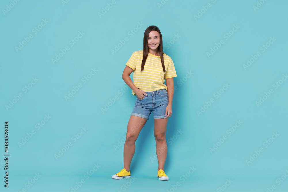 Beautiful woman wearing stylish denim shorts on light blue background Beautiful woman wearing stylish denim shorts on light blue background