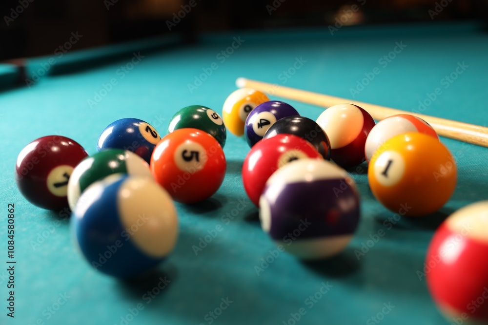 Many colorful billiard balls and cue on green table, closeup Many colorful billiard balls and cue on green table, closeup
