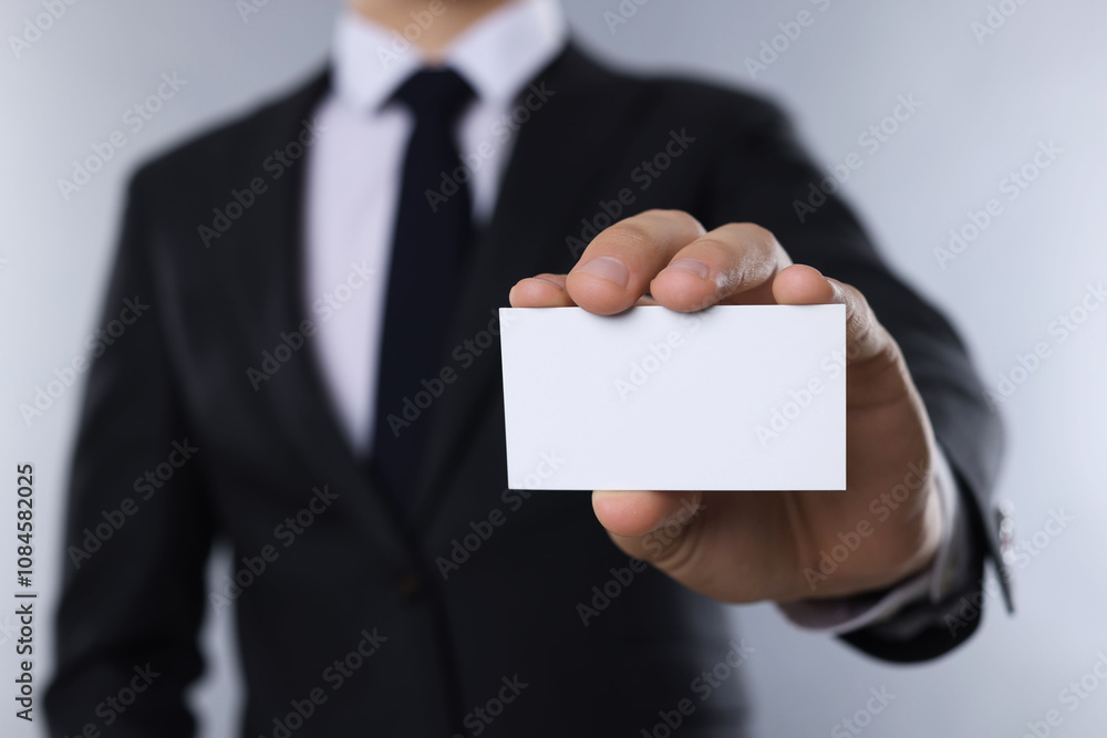 Man holding blank business card on grey background, closeup. Mockup for design Man holding blank business card on grey background, closeup. Mockup for design