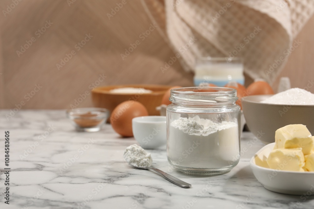 Baking powder in jar and other products on white marble table, closeup. Space for text Baking powder in jar and other products on white marble table, closeup. Space for text