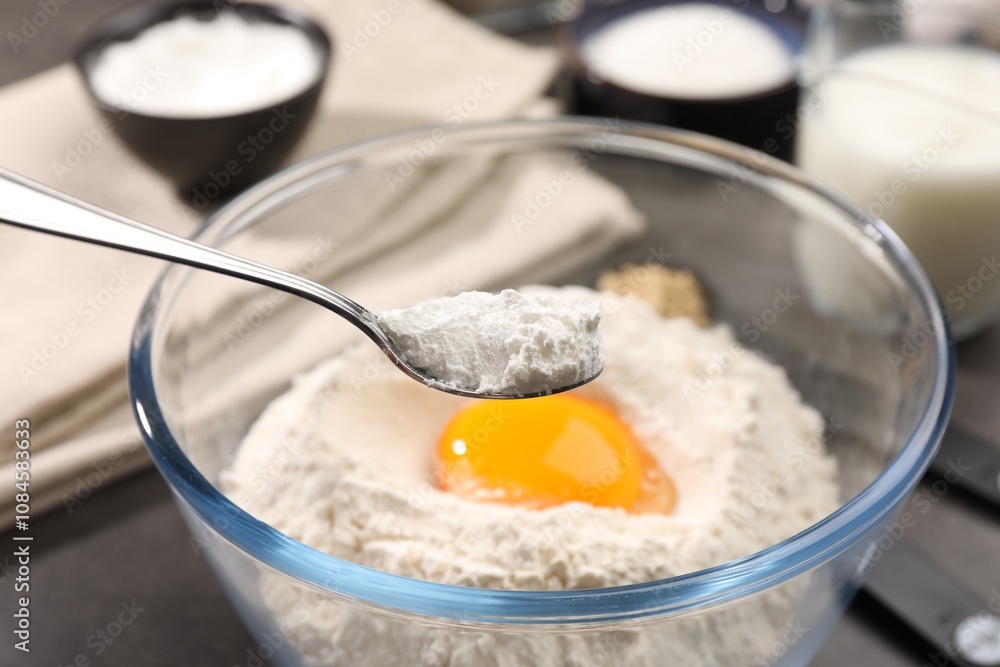 Taking baking powder from bowl with spoon at grey table, closeup Taking baking powder from bowl with spoon at grey table, closeup
