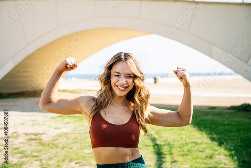 Wallpaper Mural Young sporty woman showing muscles under white bridge Torontodigital.ca