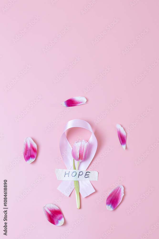 Pink ribbon with tulip and petals on a pink background. Pink ribbon with tulip and petals on a pink background.