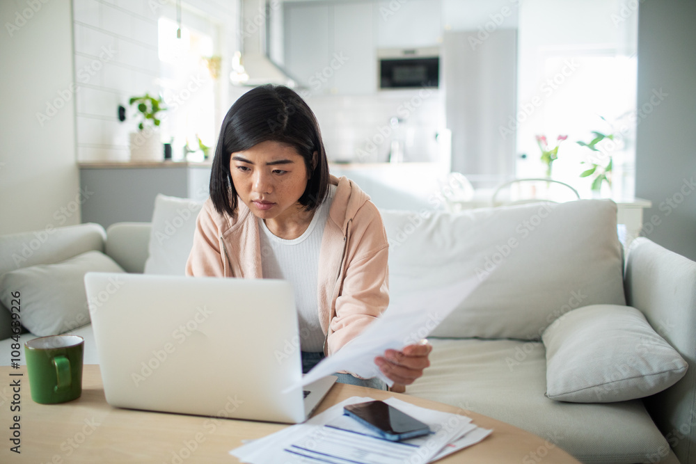 Asian woman working on laptop from home couch Asian woman working on laptop from home couch