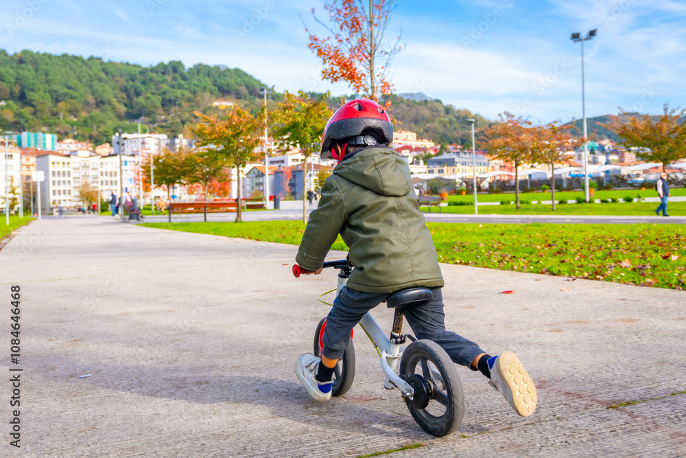 Obraz premium A young boy is riding a bicycle down a sidewalk
