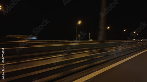 Driving a car in summer night illuminated city streets, windshield view