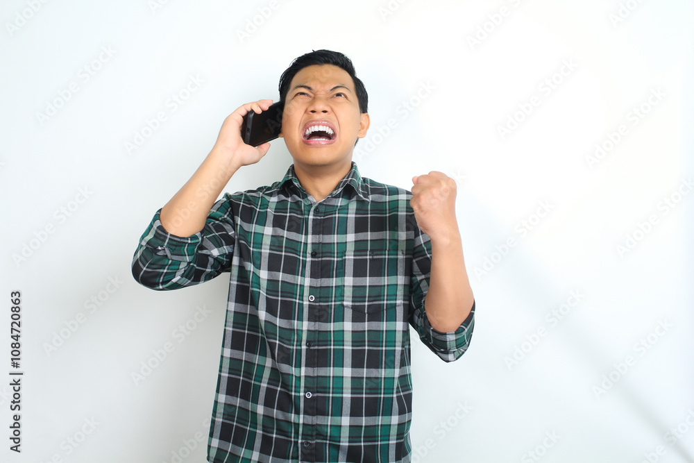 unhappy asian man wearing casual plaid shirt raising his arm show angry face while talking on cellphone isolated on white background unhappy asian man wearing casual plaid shirt raising his arm show angry face while talking on cellphone isolated on white background