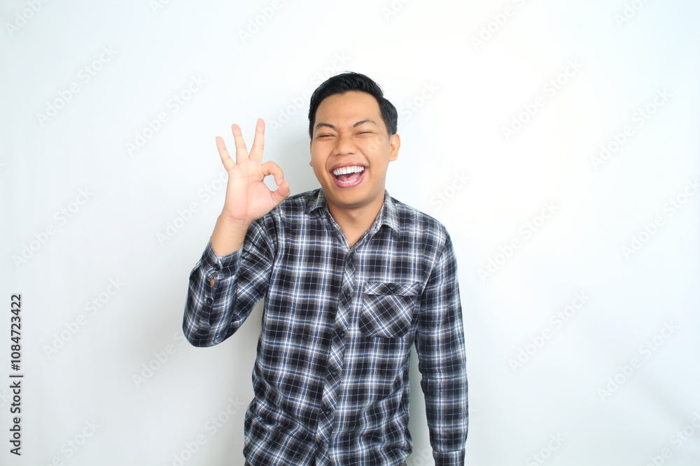 Fototapeta premium success asian man show okay signs using finger with laughing expression, accept and approved gesture, isolatd on white background, wear casual shirt