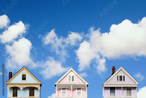 four Victorian houses in pastel colors against deep blue sky, perfect white clouds