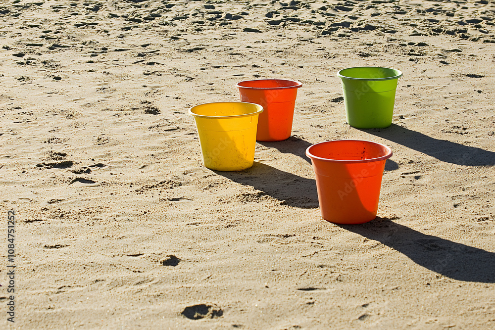 colorful plastic buckets casting shadows on sand, beach fun, sand castle construction colorful plastic buckets casting shadows on sand, beach fun, sand castle construction