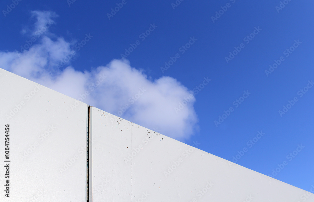 White concrete building wall against a blue sky with a cloud abstract textured background White concrete building wall against a blue sky with a cloud abstract textured background