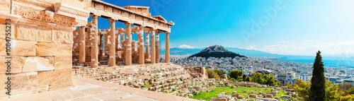 A panoramic view of the ancient Acropolis site in Athens, showcasing historic columns against a clear blue sky.