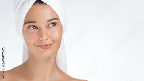 A young woman smiles gently while wrapped in a towel after completing her skincare routine. Perfect for promoting beauty, wellness, skincare, and spa treatments that emphasize healthy glowing skin and