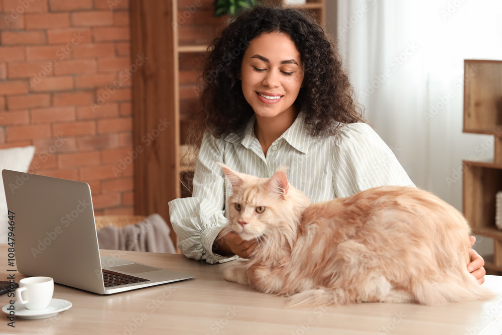 Beautiful young happy African-American woman working with laptop, cup of coffee and her cute Maine Coon cat at home Beautiful young happy African-American woman working with laptop, cup of coffee and her cute Maine Coon cat at home
