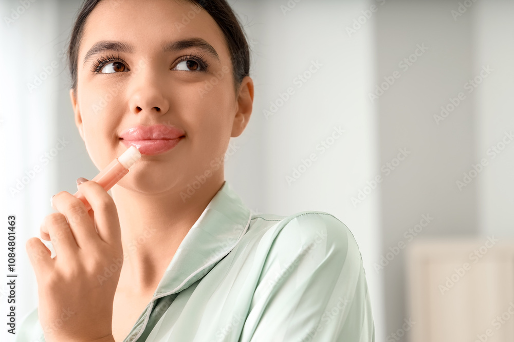 Young woman applying lip balm in bathroom, closeup Young woman applying lip balm in bathroom, closeup