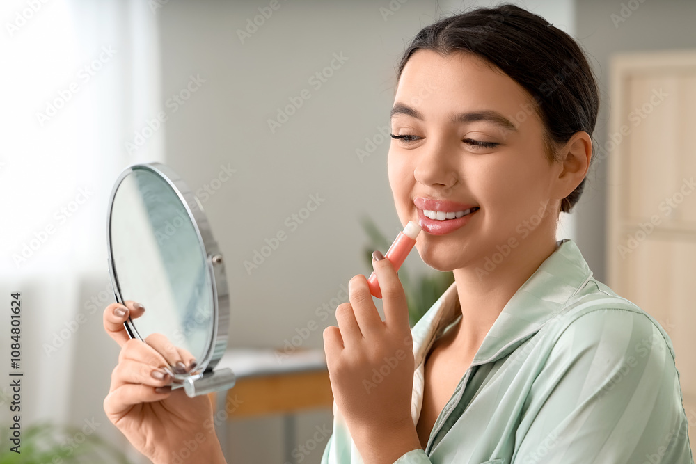 Young woman with mirror applying lip balm in bathroom, closeup Young woman with mirror applying lip balm in bathroom, closeup