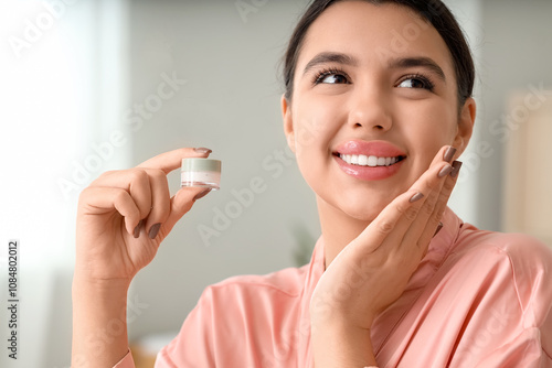 Young woman with lip balm smiling in bathroom, closeup