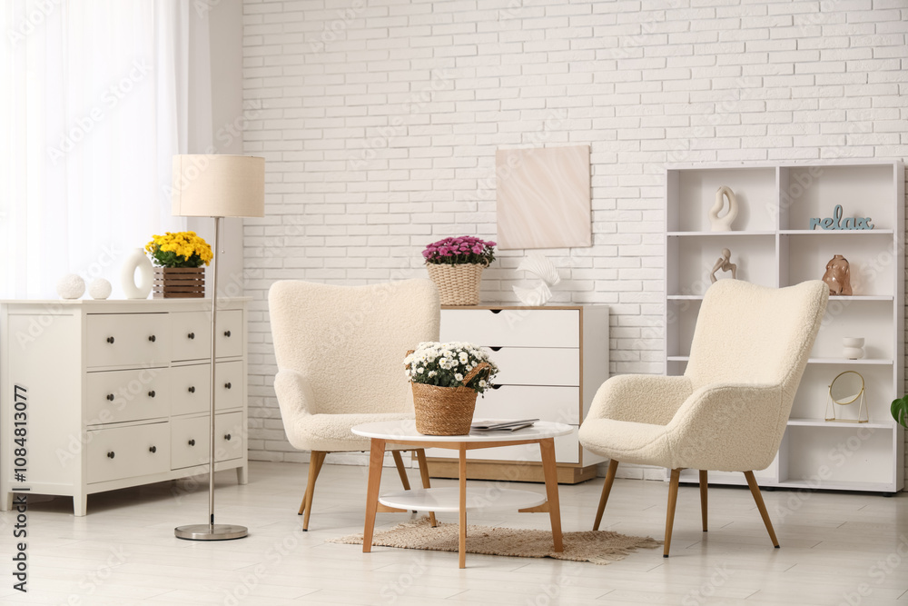 Fototapeta premium Interior of living room with armchairs, table and chrysanthemum flowers