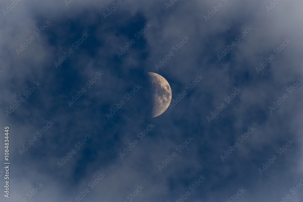 The moon in the dark blue sky with white clouds, closeup The moon in the dark blue sky with white clouds, closeup